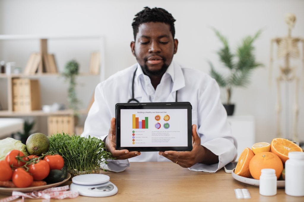 Dietitian showing tablet with diet plan on screen in office